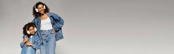 A beautiful African American mother and her adorable daughter pose in matching denim outfits, banner — Stock Photo