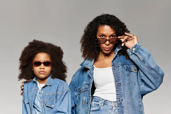 Nero mamma e figlia in denim e occhiali da sole posare in studio. — Foto stock