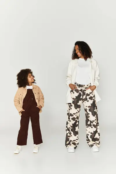 A stylish mother and daughter share smiles while showcasing their unique styles in a studio. — Stock Photo
