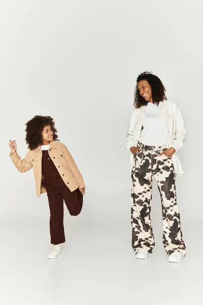A mother and daughter showcase their fashionable outfits with joy and style in a studio. — Stock Photo