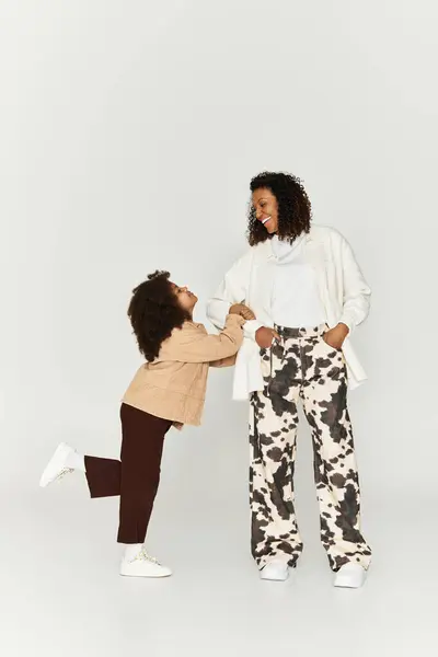 Une mère élégante et sa fille affichent leurs tenues à la mode avec joie et confiance. — Photo de stock