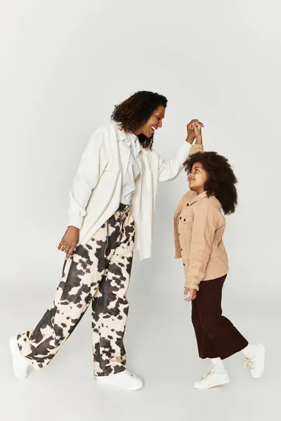 Mother and daughter share a joyful dance in stylish animal print outfits, embracing family bonds. — Stock Photo