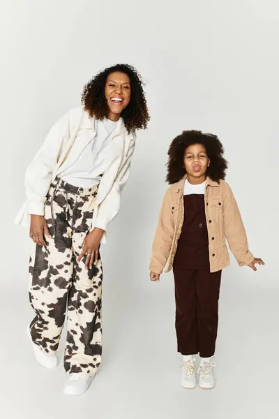 Mother and daughter showcase their unique fashion in a studio setting with a grey backdrop. — Stock Photo
