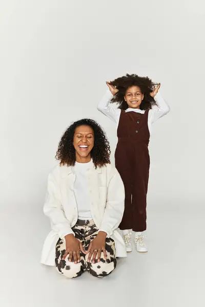Uma mãe e filha afro-americana compartilham um momento alegre em roupas elegantes. — Fotografia de Stock