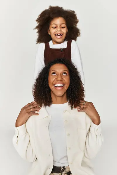 Uma mãe e filha feliz posar em roupas elegantes, destacando seu vínculo em um pano de fundo cinza. — Fotografia de Stock