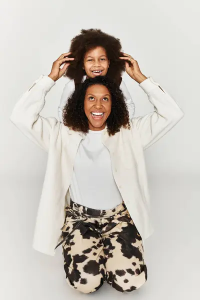 A mother and daughter share laughter in stylish animal print outfits against a grey backdrop. — Stock Photo