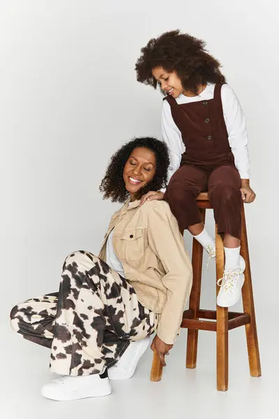 Una madre e una figlia ridono insieme in abiti eleganti in uno studio alla moda. — Foto stock