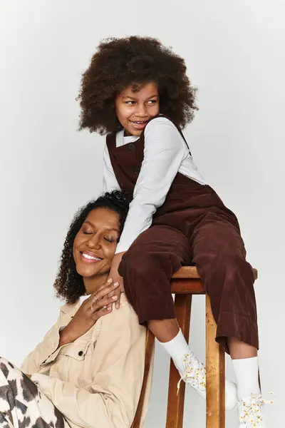 A mother and daughter wear fashionable outfits while posing joyfully in a studio. — Stock Photo