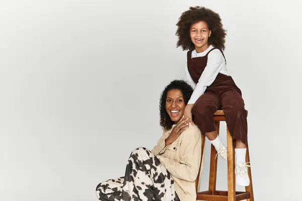 A mother and daughter express joy and style while posing in fashionable outfits in a studio. — Stock Photo
