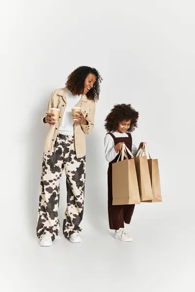 Mãe e filha desfrutar de um momento divertido juntos em roupas elegantes segurando sacos de compras. — Fotografia de Stock