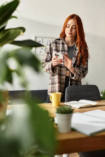 A beautiful young woman relaxes in a bright room, checking her phone surrounded by plants. — Stock Photo