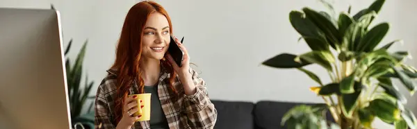 A young beautiful woman smiles as she talks on the phone while holding a cup in a cozy room. — Stock Photo
