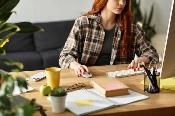 Focused young woman engages in creative work at her home workspace, surrounded by plants and books. — Stock Photo