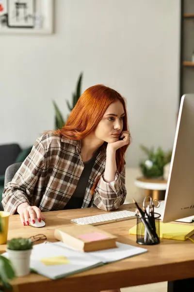 A young woman with vibrant hair focuses intently on her computer while relaxing at home. — Stock Photo