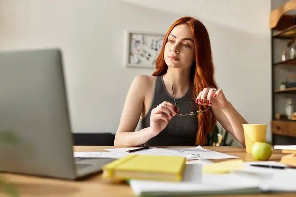 A young woman sits at her desk, surrounded by sketches, enjoying a drink thoughtfully. — Stock Photo
