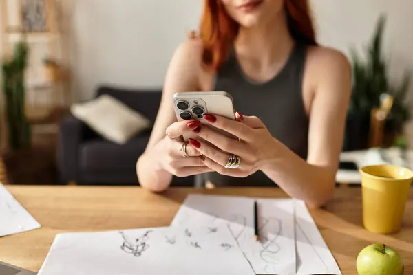 Una joven hermosa mujer disfruta de su tiempo libre en un teléfono inteligente mientras está rodeada de materiales de arte. - foto de stock