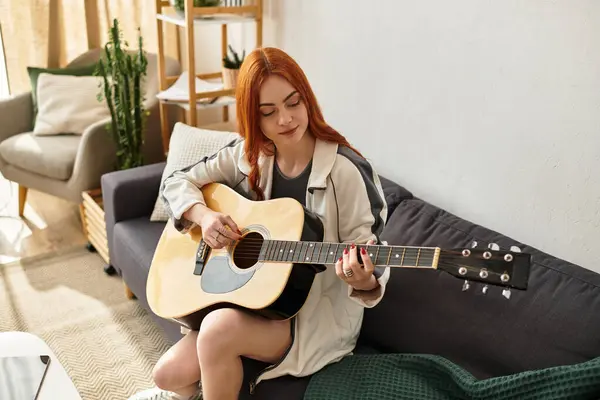 A young woman plays guitar in her cozy living space, lost in her love for music. — Stock Photo