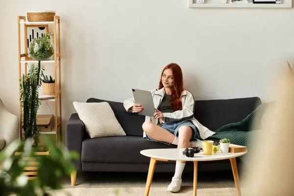 A young woman relaxes on a sofa, using her tablet in a chic living room. — Stock Photo