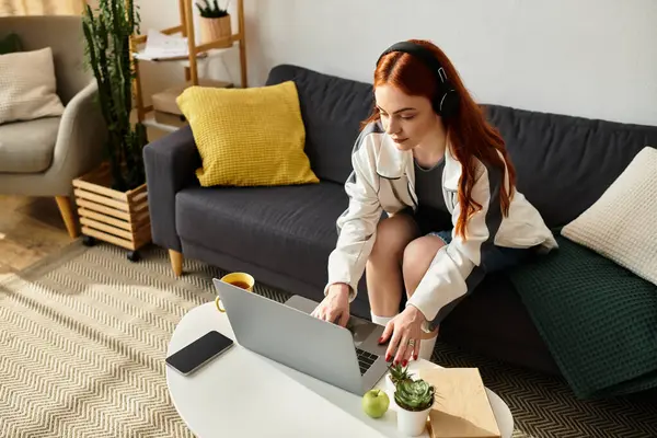 Mujer joven inmersa en su portátil, creando proyectos artísticos mientras disfruta de un ambiente acogedor. - foto de stock