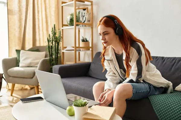A young woman relaxes on a couch, focused on her laptop screen during a leisurely afternoon. — Stock Photo