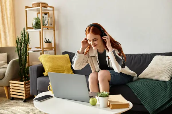 In a comfortable living room, a young woman delights in music as she unwinds on a sofa. — Stock Photo