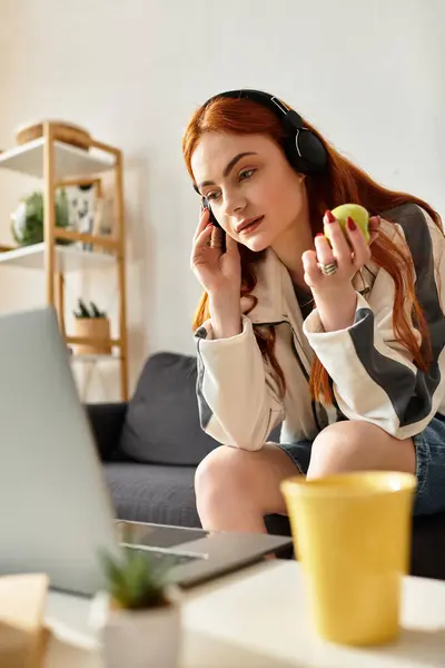 Una bella giovane donna si rilassa a casa, ascoltando musica mentre tiene in mano una mela. — Foto stock