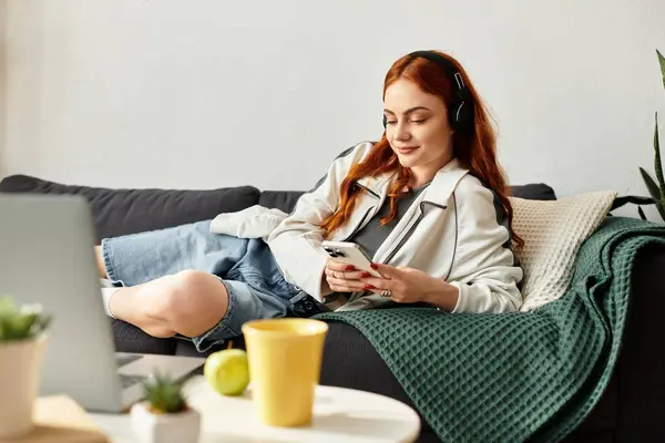 Una giovane bella donna si sdraia comodamente su un divano, immersa nella musica e nel tempo libero. — Foto stock