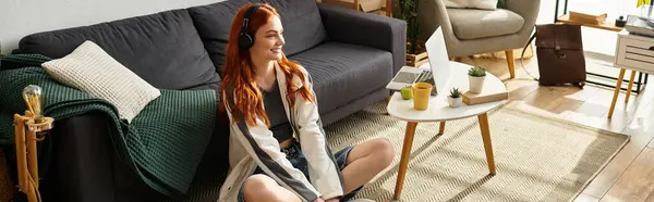 Joyful young woman sits comfortably on the floor, absorbed in her favorite tunes at home. — Stock Photo