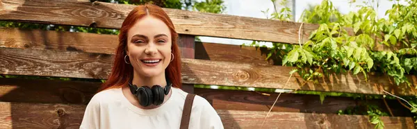 Radiant young woman enjoys her spare time under the sun, smiling with headphones around her neck. — Stock Photo