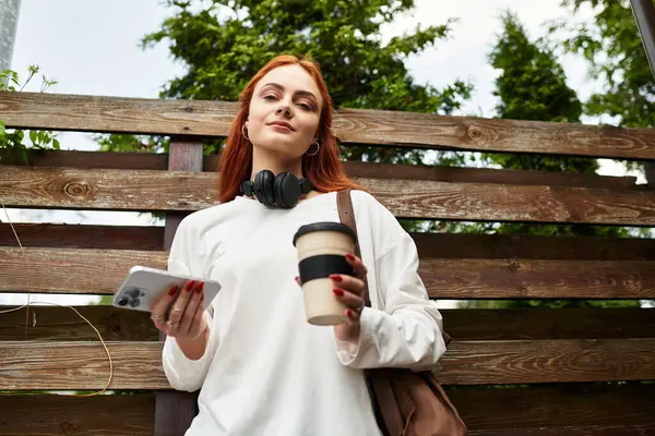 Una giovane donna si rilassa con il caffè, scorrendo sul suo telefono. — Foto stock