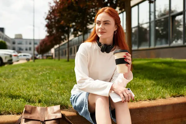 Mujer joven se relaja al aire libre, tomando café y disfrutando de la música bajo el sol. - foto de stock