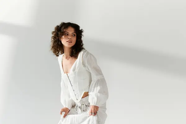 Una giovane donna elegante posa con grazia, mettendo in evidenza il suo vestito unico in uno spazio luminoso e arioso. — Foto stock