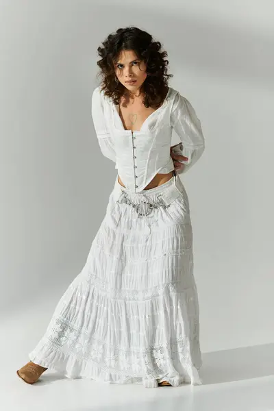 Una mujer joven posa elegantemente en un elegante traje blanco, irradiando belleza y gracia. - foto de stock