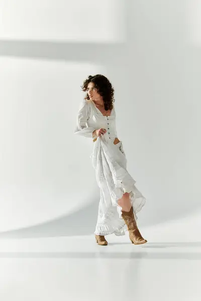 Una giovane bella donna cammina con grazia, evidenziando il suo abito bianco alla moda e stivali. — Foto stock