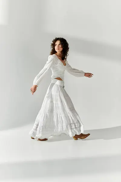 Radieuse jeune femme se pavane en toute confiance dans une tenue blanche fluide, incarnant l'élégance de la mode moderne. — Photo de stock