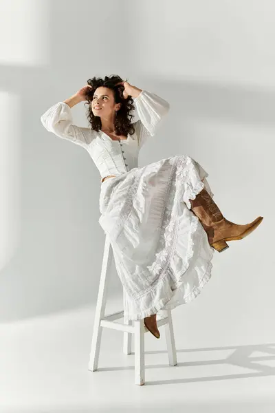 Une jeune femme élégante pose sur un tabouret, exsudant confiance et élégance dans sa tenue. — Photo de stock