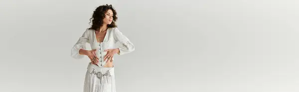 Elegante mujer joven muestra atuendo de moda mientras que golpea una pose en un espacio moderno. - foto de stock