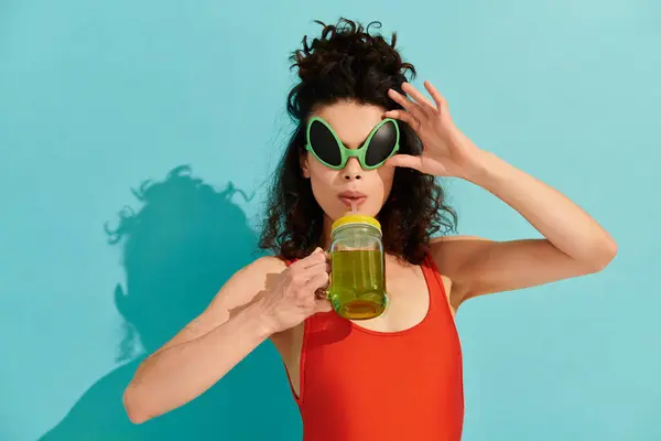 Schöne junge Frau posiert mit Alien-Sonnenbrille und einem erfrischenden Getränk in der Hand. — Stockfoto