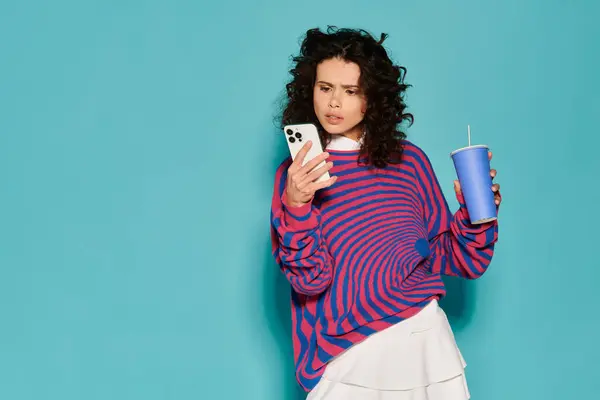Elegantemente vestita donna esamina il suo telefono mentre si gode una bevanda rinfrescante in un ambiente luminoso — Foto stock