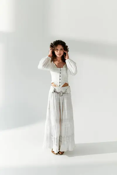 A young woman wearing a stylish outfit stands confidently in a bright, minimalist studio. — Stock Photo