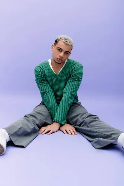 Un jeune homme afro-américain pose avec confiance dans une tenue tendance sur un fond violet frappant. — Photo de stock