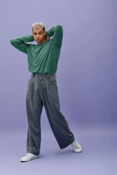 Un giovane uomo afroamericano posa con fiducia in abiti alla moda con uno sfondo viola audace. — Foto stock