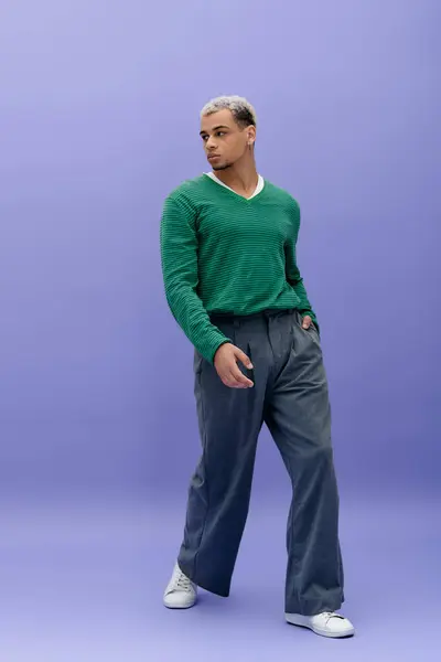 Elegante giovane uomo afroamericano posa con fiducia in un vestito alla moda su uno sfondo colorato. — Foto stock