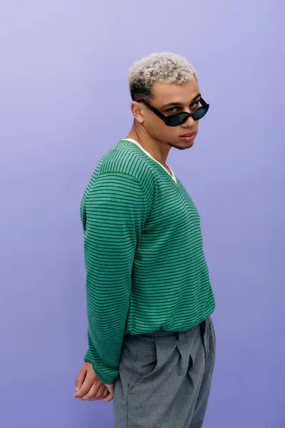A stylish young African American man with dyed hair poses confidently against a purple background. — Stock Photo