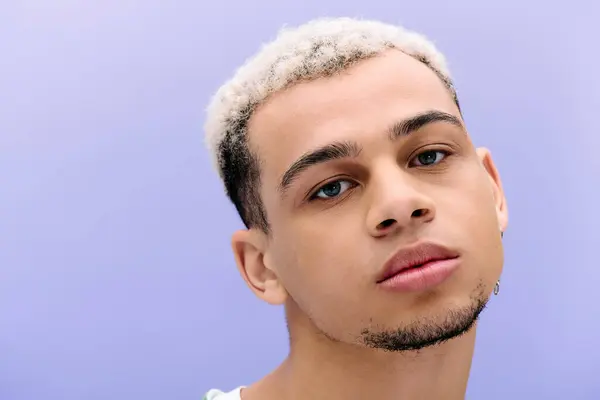 A stylish young Black man with dyed hair poses against a purple backdrop. — Stock Photo
