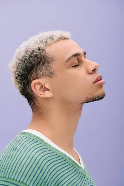 Un giovane uomo afroamericano con i capelli tinti mette in mostra il suo abito elegante in una posa accattivante. — Foto stock