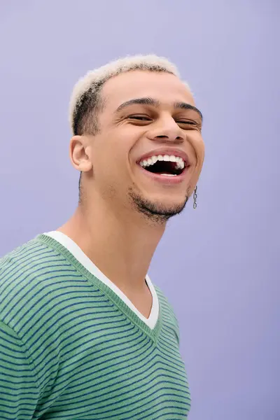 Un jeune homme aux cheveux teints affiche un sourire éclatant tout en posant dans une tenue élégante. — Photo de stock