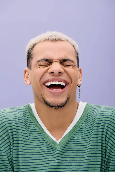 Un joven negro alegre se ríe con un atuendo elegante, rodeado de púrpura. - foto de stock