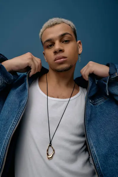 A young african american man poses confidently in a denim jacket, showcasing his unique style. — Stock Photo