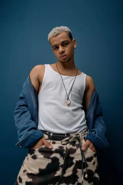 Un joven confiado en una chaqueta de mezclilla muestra su estilo único con el pelo teñido. - foto de stock